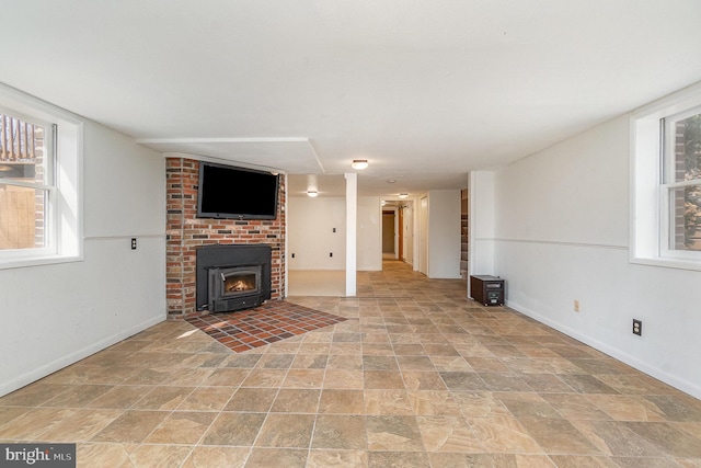 unfurnished living room featuring stone finish floor, a wood stove, and baseboards