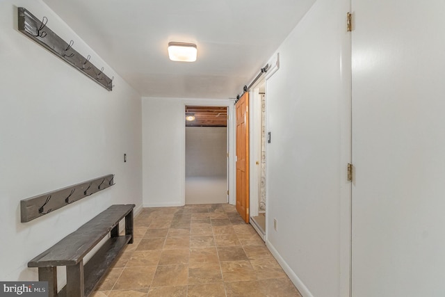 hall with a barn door, baseboards, and stone finish flooring