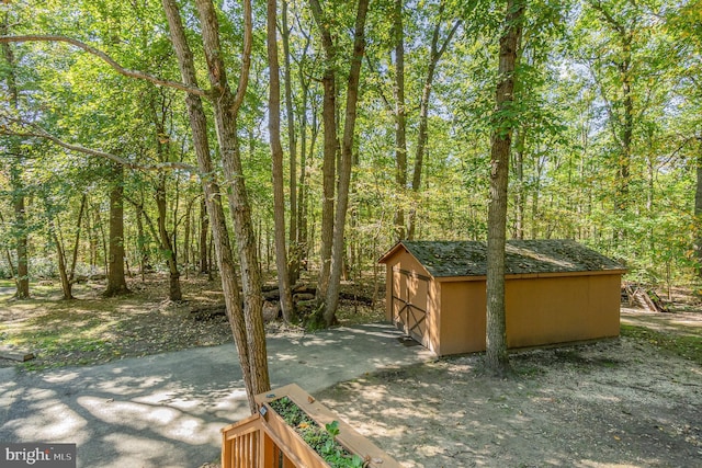 view of yard featuring an outdoor structure and a view of trees