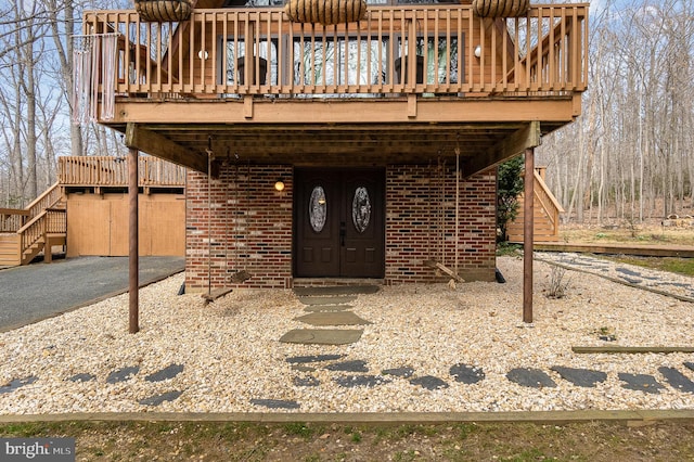 entrance to property featuring brick siding and a wooden deck