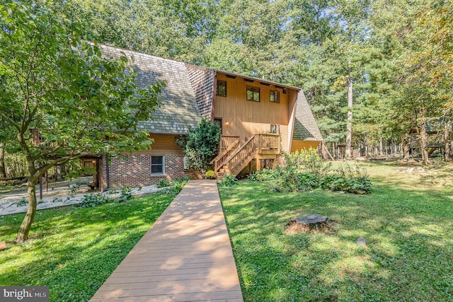 view of front of home featuring stairway, roof with shingles, and a front lawn