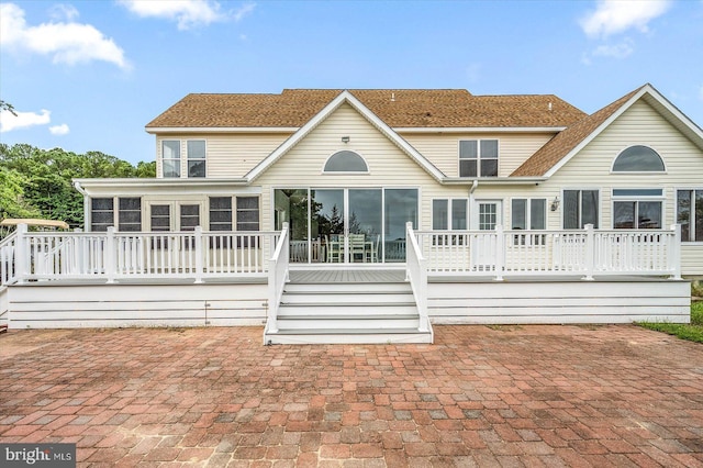 rear view of property featuring a wooden deck, a patio, and a sunroom