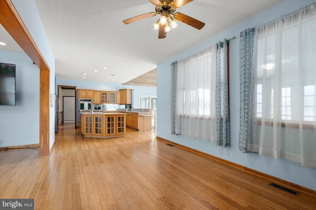 kitchen with visible vents, light wood finished floors, light countertops, glass insert cabinets, and a center island