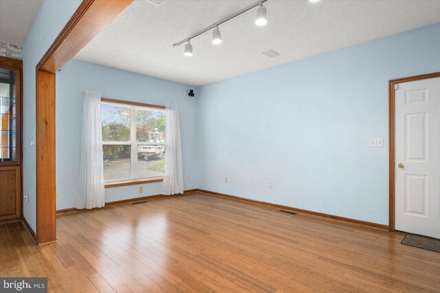 empty room with visible vents, light wood-style flooring, and baseboards