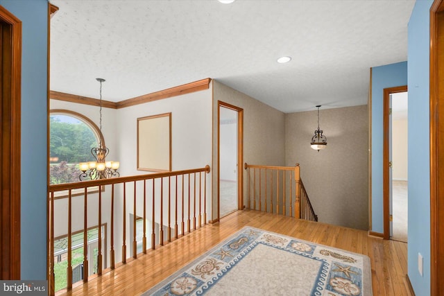 corridor featuring an upstairs landing, an inviting chandelier, and wood finished floors