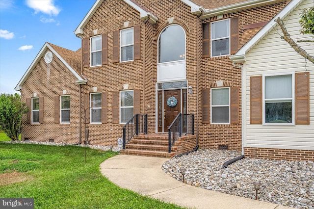 view of front facade with crawl space, brick siding, and a front yard