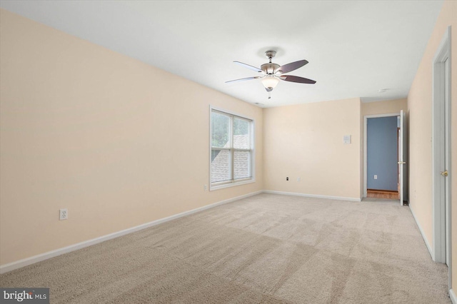 spare room with a ceiling fan, light colored carpet, and baseboards