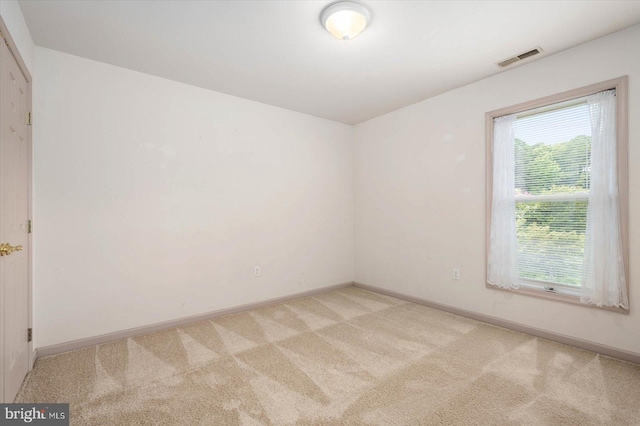 unfurnished room featuring visible vents, light colored carpet, and baseboards