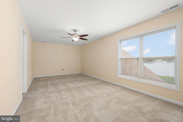 empty room with visible vents, light colored carpet, baseboards, and ceiling fan