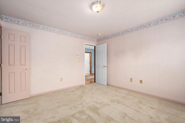 empty room featuring carpet and baseboards