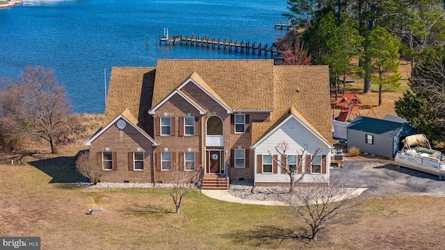 view of front of house with a front lawn, brick siding, and a water view