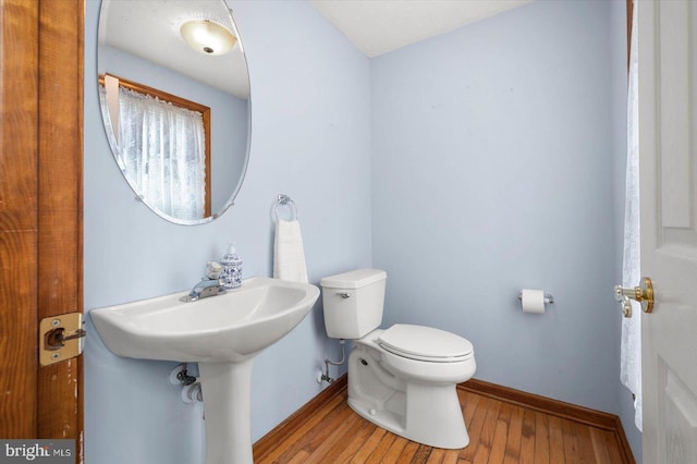 bathroom with baseboards, toilet, and wood finished floors