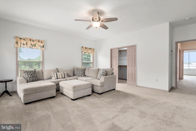 carpeted living room with baseboards and a ceiling fan