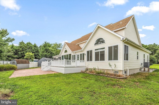 rear view of house featuring a wooden deck, a yard, an outdoor structure, a storage shed, and a patio area