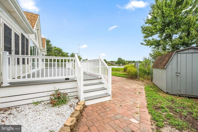 view of patio featuring a deck, a storage shed, and an outdoor structure