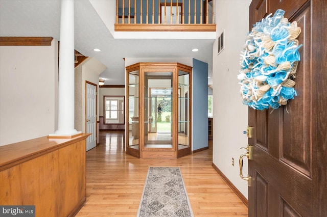 entryway featuring baseboards, visible vents, ornate columns, and light wood-type flooring