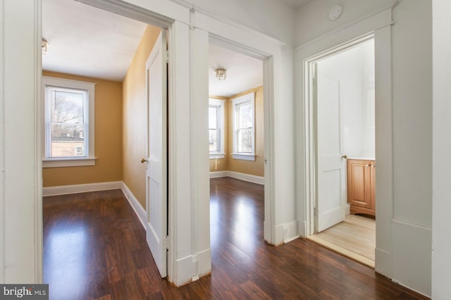 hallway with baseboards and dark wood-style floors