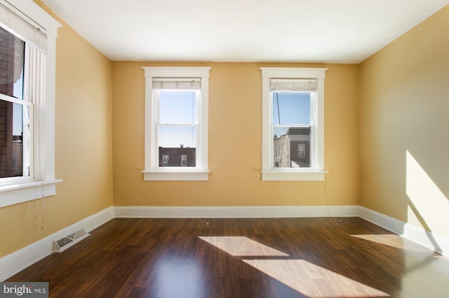 unfurnished room featuring wood finished floors, visible vents, and baseboards