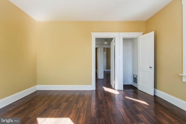 empty room featuring baseboards and dark wood-style floors