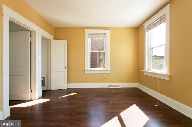 empty room with visible vents, baseboards, and wood finished floors