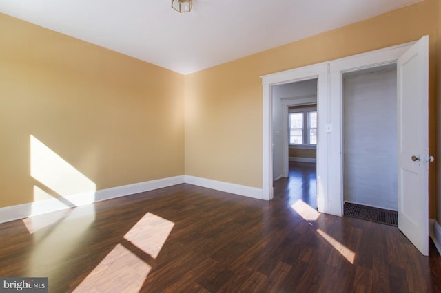 empty room with dark wood-type flooring and baseboards