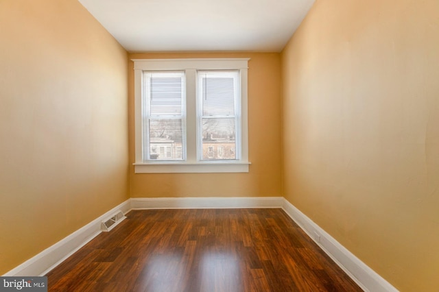 unfurnished room featuring dark wood finished floors, baseboards, and visible vents