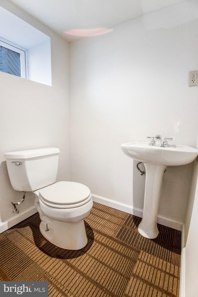 half bath featuring toilet and baseboards