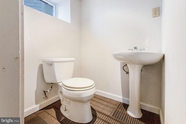 half bath featuring tile patterned flooring, toilet, and baseboards