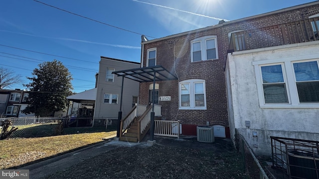 view of front of property with brick siding, central AC unit, entry steps, and fence