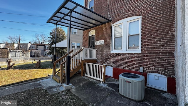 exterior space featuring central air condition unit, fence, and a lawn