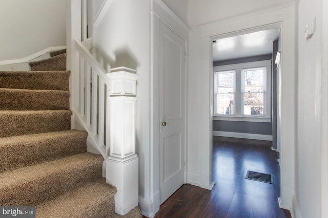 stairs featuring visible vents, baseboards, and wood finished floors