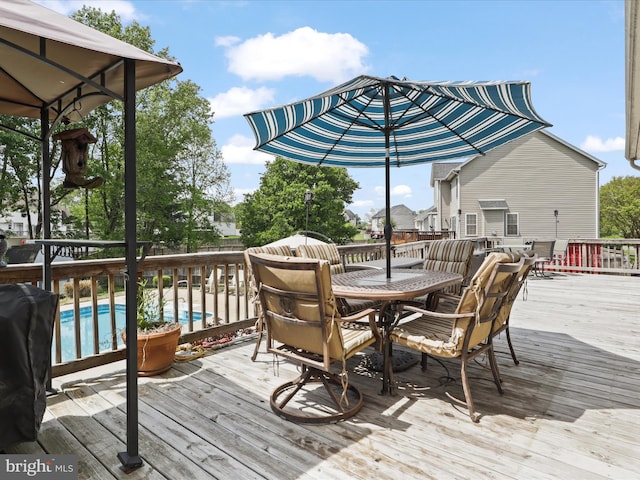 wooden terrace featuring outdoor dining area and a fenced in pool