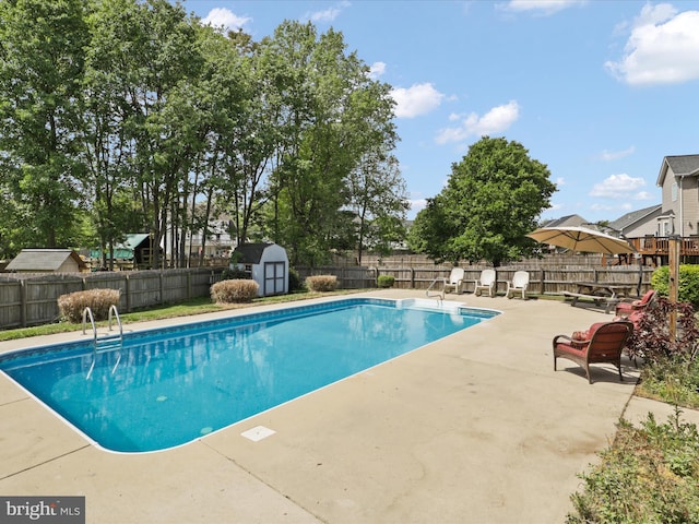view of pool featuring a patio area, an outbuilding, a fenced in pool, a fenced backyard, and a storage unit