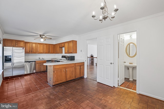 kitchen featuring light countertops, ceiling fan with notable chandelier, a peninsula, stainless steel appliances, and a sink