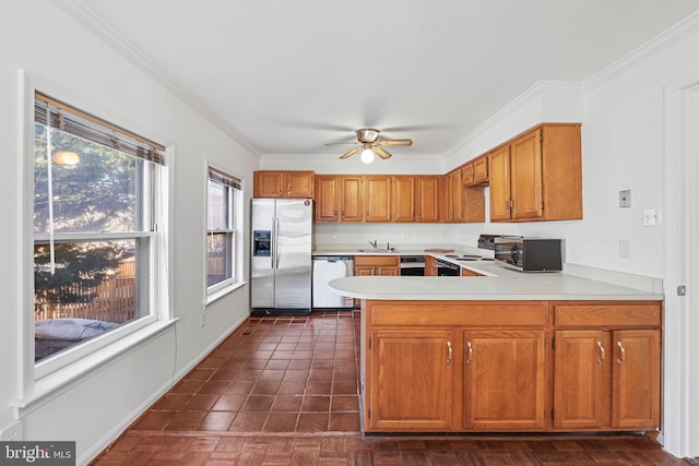 kitchen featuring a ceiling fan, a peninsula, light countertops, appliances with stainless steel finishes, and brown cabinets