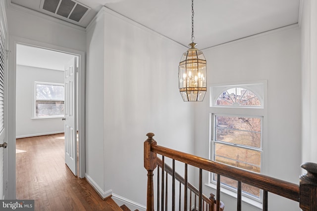 hallway with baseboards, visible vents, dark wood-style flooring, an upstairs landing, and a chandelier