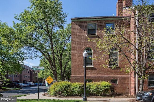 view of front of property featuring brick siding and a chimney