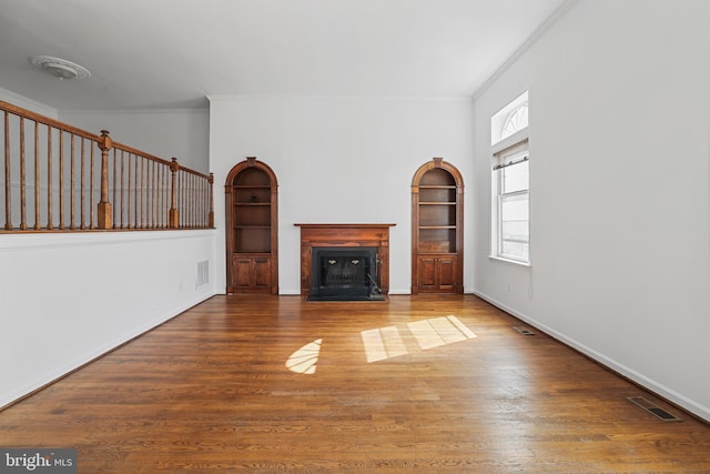 unfurnished living room with visible vents, wood finished floors, a fireplace, and ornamental molding