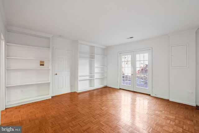 empty room featuring visible vents, built in shelves, french doors, crown molding, and baseboards