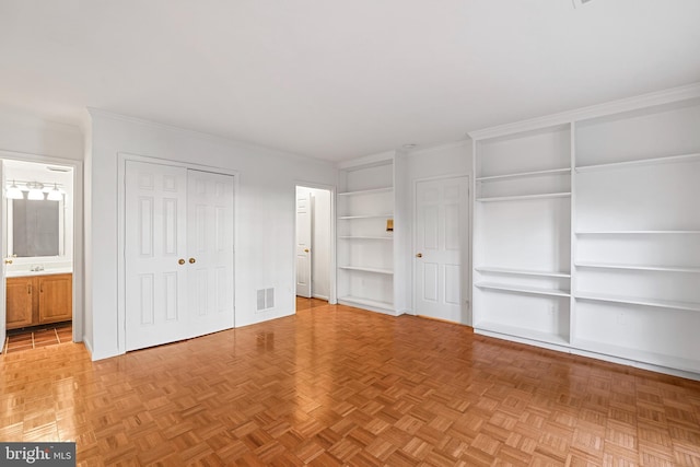 unfurnished bedroom with visible vents, two closets, and ornamental molding