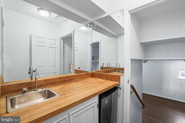 kitchen with butcher block countertops, a sink, dark wood-style floors, white cabinetry, and wine cooler