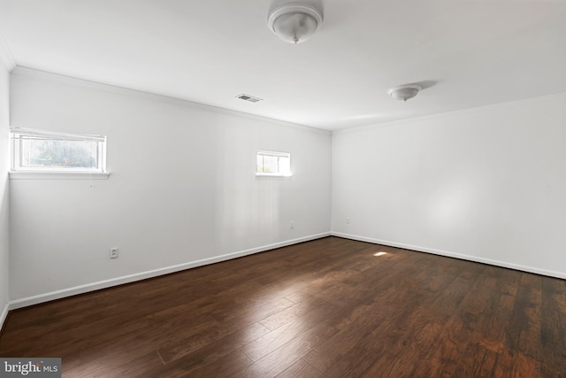 unfurnished room with visible vents, crown molding, baseboards, and wood finished floors