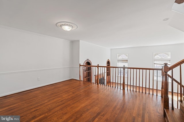 empty room with ornamental molding, baseboards, and wood finished floors