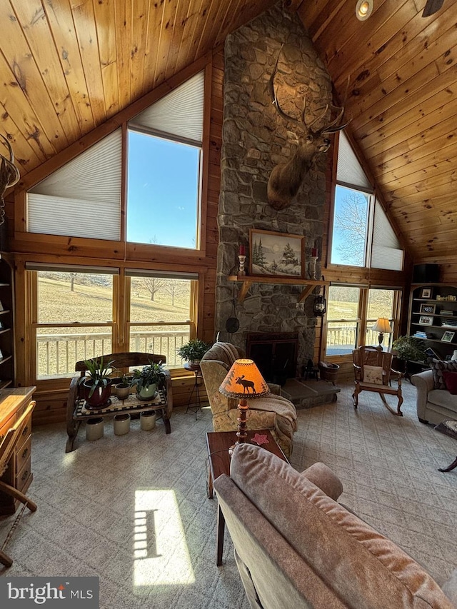 carpeted living room with a stone fireplace, wood ceiling, and high vaulted ceiling