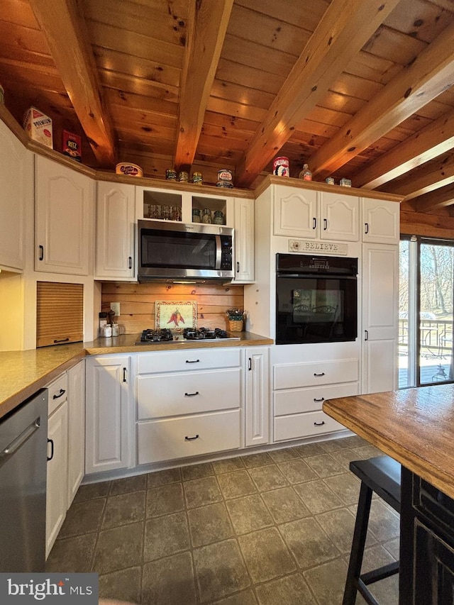 kitchen featuring stainless steel appliances, beam ceiling, and white cabinets