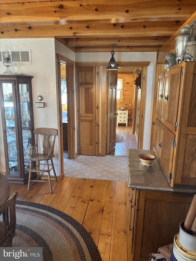 interior space featuring visible vents, beam ceiling, and light wood-style flooring