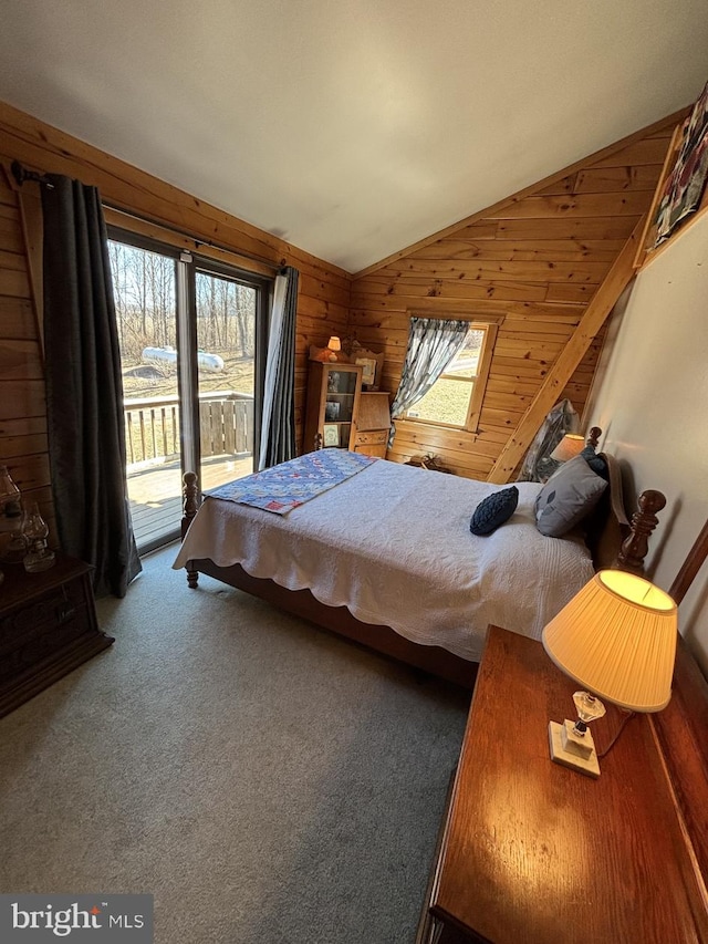 carpeted bedroom with access to outside, wood walls, multiple windows, and vaulted ceiling