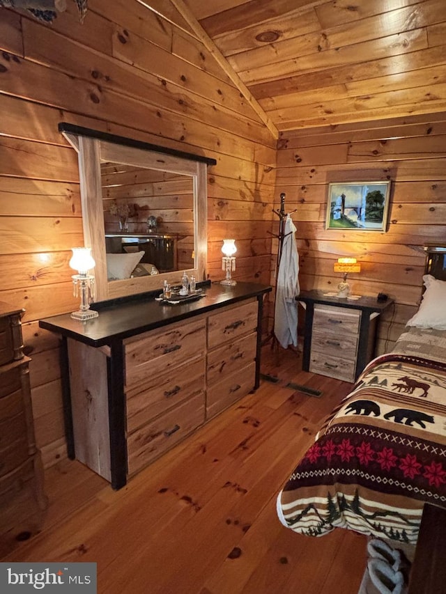 bedroom with vaulted ceiling, hardwood / wood-style flooring, wooden ceiling, and wood walls