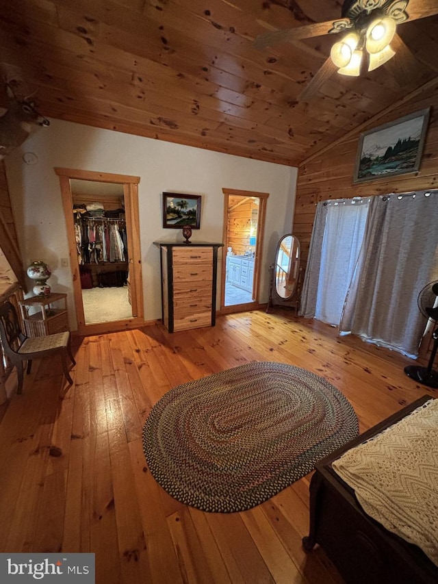 interior space with a walk in closet, light wood-style flooring, a ceiling fan, wood ceiling, and vaulted ceiling