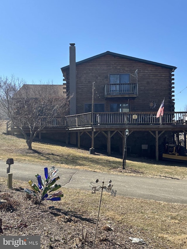 rear view of property featuring a wooden deck and a chimney